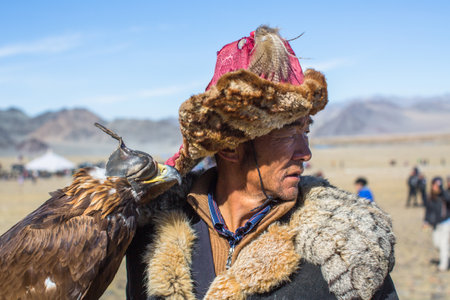 OLGIY, MONGOLIA - SEP 30, 2017: Kazakh Golden Eagle Hunter at traditional clothing, with a golden eagle on his arm during annual national competition with birds of prey "Berkutchi" of West Mongolia.のeditorial素材