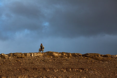 SAGSAY, MONGOLIA - SEP 28, 2017: Golden Eagle Hunter, while hunting to the hare holding a golden eagles on his arms in desert mountain of Western Mongolia.のeditorial素材