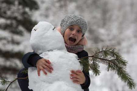 Girl child and a snowman. Winter kids games.の写真素材
