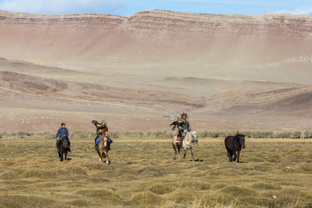 SAGSAY, MONGOLIA - SEP 28, 2017: Eagle Hunters traditional clothing, while hunting to the hare holding a golden eagles on his arms in desert mountain of Western Mongolia.のeditorial素材