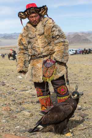 OLGIY, MONGOLIA - SEP 30, 2017: Kazakh Eagle Hunter traditional clothing, with a golden eagle on his arm during annual national competition with birds of prey "Berkutchi" of Western Mongolia.のeditorial素材