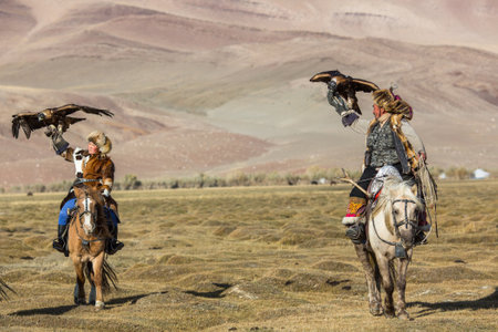SAGSAY, MONGOLIA - SEP 28, 2017: Kazakh Eagle Hunter (Berkutchi) with horse teaches his daughter to...
