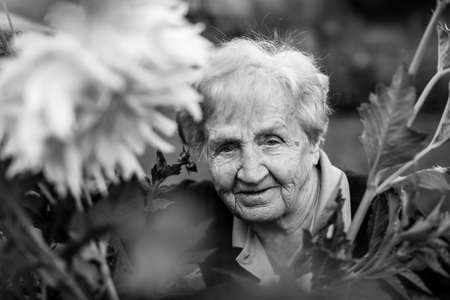 Black and white portrait of an elderly woman in the garden.