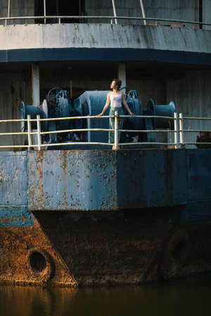 Young beautiful mixed race woman stands on an abandoned giant ship.の写真素材