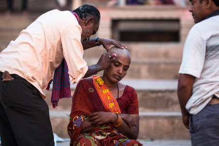 VARANASI, INDIA - MAR 23, 2018: Hairdresser cuts hair of the pilgrim. A haircut in Varanasi is considered to be a kind of purification ritual in Hinduism.のeditorial素材