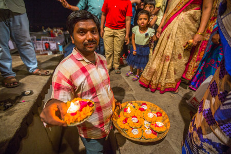 VARANASI, INDIA - MAR 17, 2018: Presenting flowers and candles to holy Ganges river. According to...