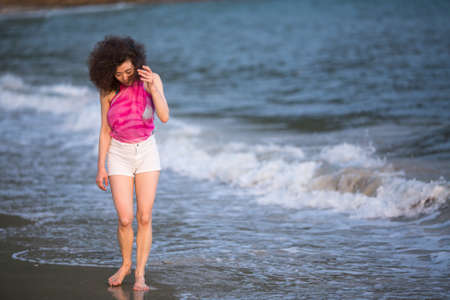 Young beautiful mixed race woman on the surf line at sea beach.の写真素材