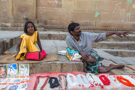 VARANASI, INDIA - MAR 23, 2018: Street seller on the banks of the sacred Ganges river selling souvenirs and small garlands for Hindu devotees to use in their devotions.のeditorial素材