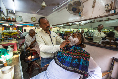 VARANASI, INDIA - MAR 16, 2018: Hairdresser cuts hair of the pilgrim. A haircut in Varanasi is considered to be a kind of purification ritual in Hinduism.のeditorial素材