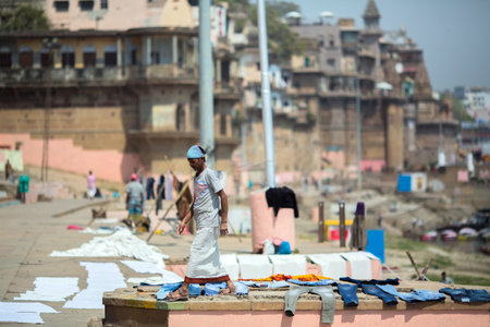 VARANASI, INDIA - MAR 14, 2018: A man washes sheets in the Holy Ganga river. Varanasi is one of the most important pilgrimage sites in India and is one of the 7 sacred cities of Hinduism.のeditorial素材