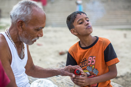 VARANASI, INDIA - MAR 16, 2018: Unidentified indian street children and a grown man on the banks of Ganga river. According to legends, the city was founded by God Shiva about 5000 years ago.のeditorial素材