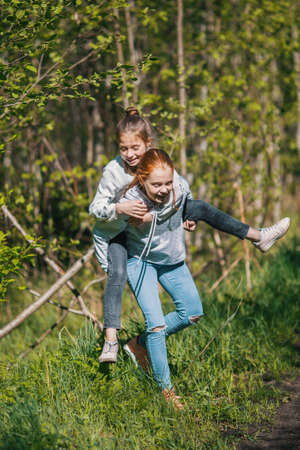 Two sisters girls friends teenagers having fun in the Park at summer.