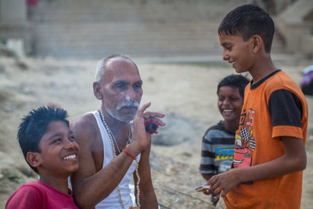 VARANASI, INDIA - MAR 16, 2018: Unidentified indian street children and a grown man on the banks of Ganga river. According to legends, the city was founded by God Shiva about 5000 years ago.のeditorial素材