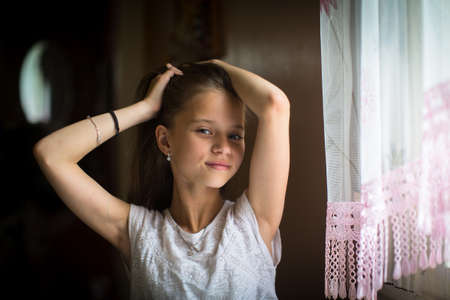 Cute ten-year-old girl posing for the camera sitting at the table.