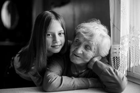 A little girl hugs her grandmother. Black and white portrait.