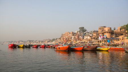 VARANASI, INDIA - MAR 26, 2018: View from a boat glides through water on Ganges river along shore of...