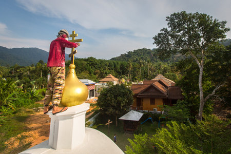 KOH CHANG, THAILAND - FEB 24, 2018: Orthodox Priest refreshes crosses on domes of the church. There are currently 10 Orthodox parishes in Thailand and Orthodoxy is practiced by 0.002% of population.のeditorial素材