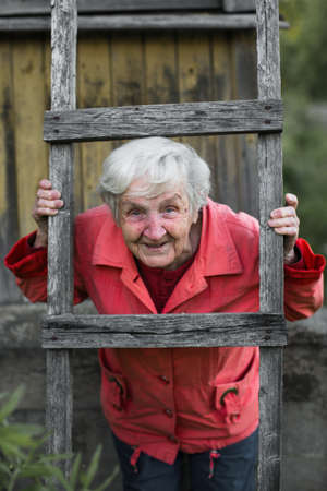 An elderly woman posing for the camera near the village house.
