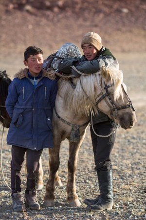 SAGSAY, MONGOLIA - SEP 28, 2017: Young men Eagle Hunters standing near their horses during hunting in the mountain desert of Western Mongolia.のeditorial素材