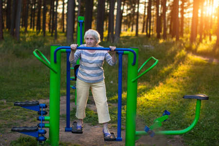 Elderly woman doing morning exercise on the street sport playground.