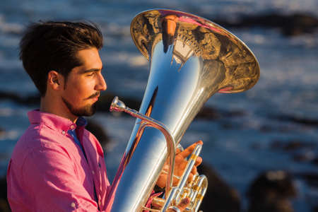 Musician play to Tuba on romantic sea shore.の写真素材