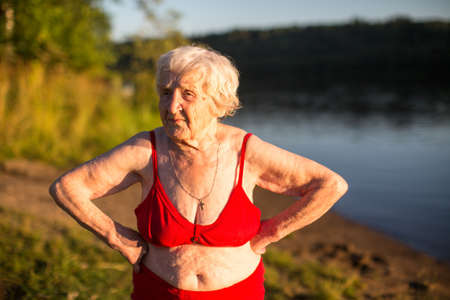 Elderly woman in a swimsuit is on the river bank.の写真素材