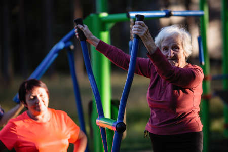 Elderly woman is doing exercises on the sport playground in the Park.の写真素材