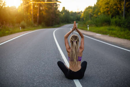Woman yoga sitting in the middle of a motorway road meditating in a Lotus position.の写真素材