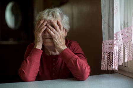 Elderly woman covering face with her hands playfully peeking through fingers.の素材 [FY310106126087]