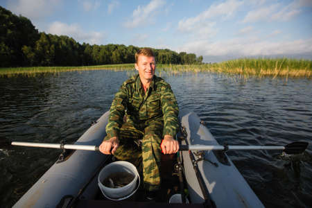 Fisherman fishing rod to fish on the lake with a rubber boat.の写真素材