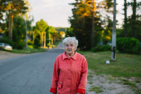 An elderly woman walking down the street in the village.の写真素材