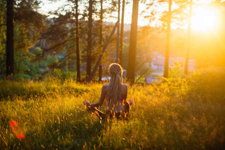 Silhouette of yoga woman on a picturesque glade in a green forest.の写真素材
