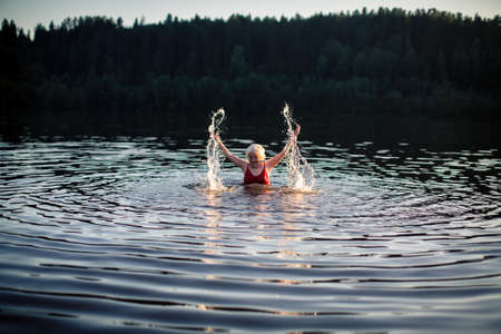 Elderly woman swimming in the summer river.の写真素材