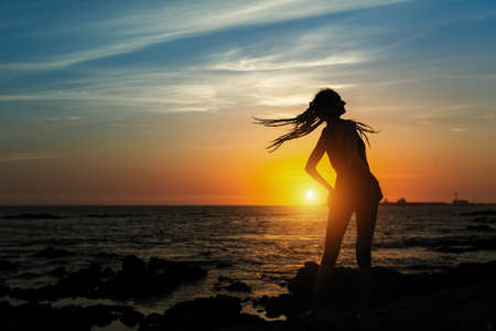 Fitness exercises girl silhouette on the sea during sunset. Healthy lifestyle.の写真素材