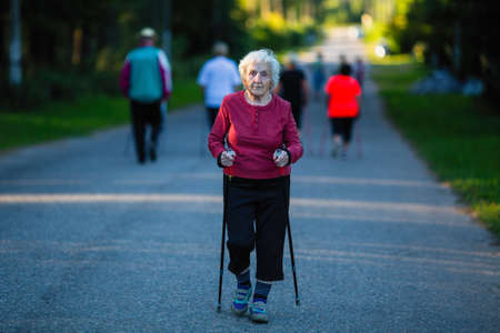 Elderly woman engaged in Nordic walking with sticks.の写真素材