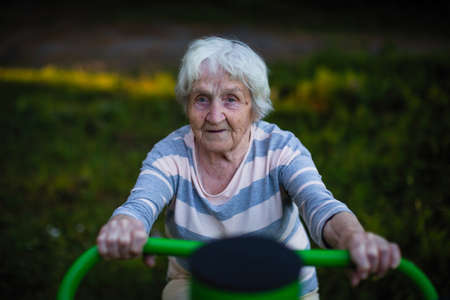 Elderly woman doing exercise on the street sport playground.