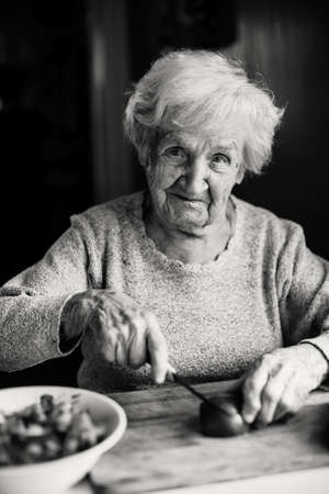 Elderly woman preparing vegetables for a salad. Black and white photo.の写真素材