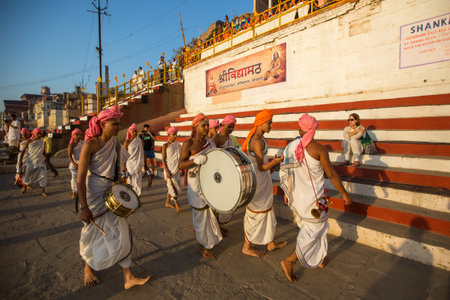VARANASI, INDIA - MAR 18, 2018: Young hindu monks conduct a ceremony to meet the dawn on the banks...