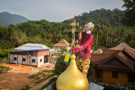KOH CHANG, THAILAND - FEB 24, 2018: Orthodox Priest refreshes crosses on domes of the church. There are currently 10 Orthodox parishes in Thailand and Orthodoxy is practiced by 0.002% of population.のeditorial素材
