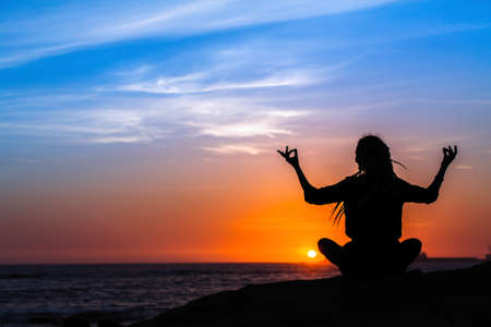 Yoga silhouette meditation girl on the sea during sunset.の写真素材
