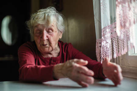 Emotions of elderly woman sitting at the table. 90 year old.の写真素材