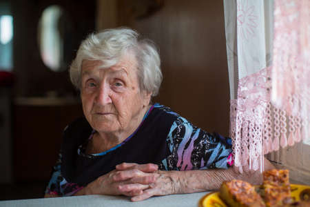 Portrait of an elderly woman has breakfast sitting at home.の写真素材