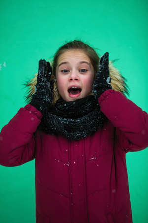 Ten-year-old girl in the winter near the green wall.の写真素材