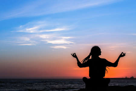 Yoga silhouette woman on the ocean during sunset. Fitness and healthy lifestyle.の写真素材