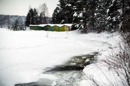 Frozen river covered with ice and snow in the village at winter.