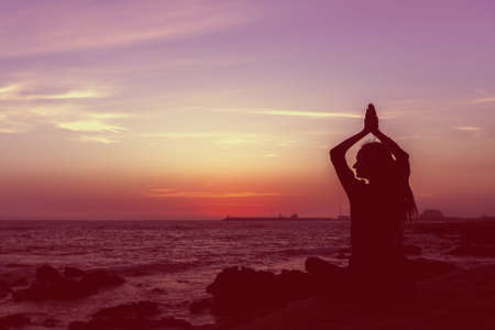 Silhouette yoga woman on the beach at sunset. Meditation.の写真素材