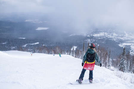 Female snowboarder freerider rides a snowboard on a snowy slope.の写真素材