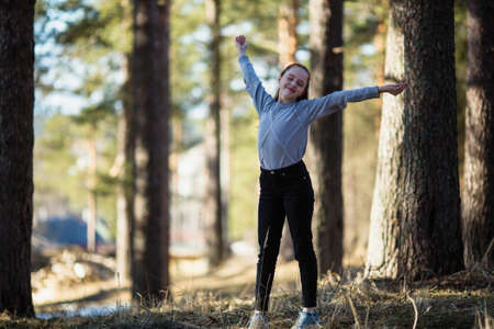 Cute teen girl is fooling around in a pine Park.の写真素材