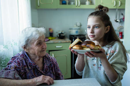 An old woman feeds her granddaughter breakfast.の写真素材