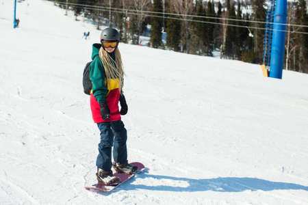 Young woman with a snowboard on a snowy slope.の写真素材